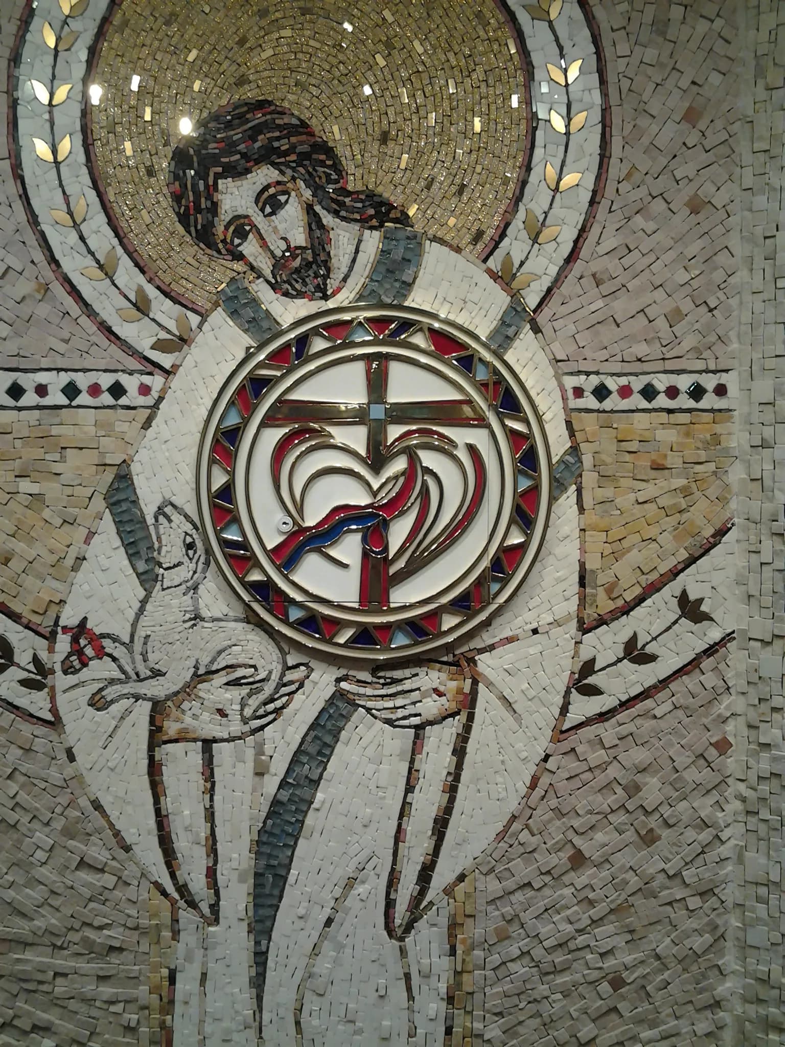 Detalhe da porta do sacrário embutida no mosaico, em metal esmaltado com cruz e coração